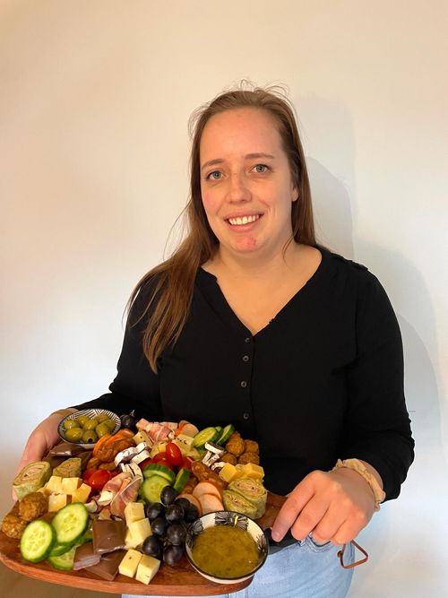 Mandy die lachend een borrelplank vasthoudt met lekkernijen.